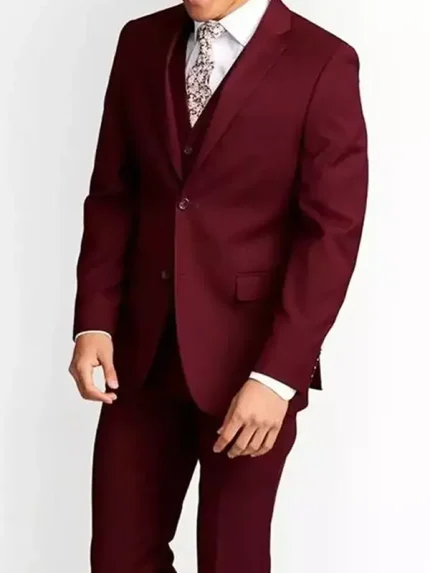 Male model wearing a maroon slim fit three piece suit with blazer and waistcoat, styled with a white shirt and patterned tie on a white background.