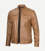 A three-quarter front view of a camel brown real leather cafe racer jacket. The jacket features a snap-tab mandarin collar, a smooth zip front, and horizontal zippered chest pockets.