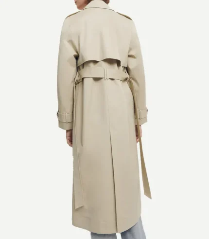 The back view of the same beige trench coat, highlighting its functional details. It features a traditional storm flap (rain guard) across the shoulders, a matching fabric belt cinched at the waist, and a long central vent at the hem for movement. Epaulets are visible on the shoulders, and the sleeves have adjustable buttoned cuffs.