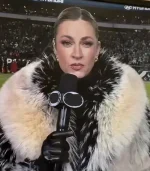 A television screen capture of Erin Andrews reporting from a stadium. The focus is on the dramatic, oversized collar of her cream and black fur coat, which frames her face. She has her hair slicked back and is holding a microphone.