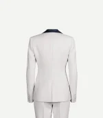 The rear view of a white women’s tuxedo jacket. The image highlights the tailored construction, including a single center vent at the hem, structured shoulders, and four small buttons on each sleeve cuff. The navy blue satin collar is visible at the neck.