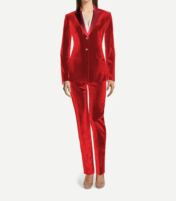 Womens Red Cotton Velvet Tuxedo A full-length front view of a woman wearing a tailored bright red cotton velvet tuxedo. The outfit includes a slim-fit blazer with peak lapels in a matching red satin, two gold buttons, and matching straight-leg velvet trousers. She is wearing a white collared shirt underneath and neutral-toned pointed-toe flats.