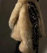 The back view of a plush, oversized fur coat. The coat is primarily a light tan or cream color with a bold, wide vertical stripe of black and white textured fur running down the center of the back.