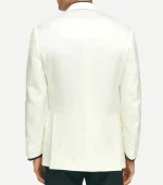 A rear view of a man wearing a structured, off-white dinner jacket. The jacket features a clean back with dual side vents and four buttons on each sleeve cuff. He is wearing black trousers that contrast with the light-colored jacket.