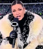 A close-up of Erin Andrews Fur Coat facial expression and the upper portion of the fur coat. The lighting highlights the individual fibers of the cream fur and the gold jewelry she is wearing.