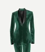 A studio product shot of a women’s emerald green velvet tuxedo jacket and matching trousers against a plain white background. The jacket features a slim fit, a single-button closure, and a contrasting black satin shawl lapel.
