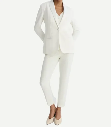 A full-length front view of a womans white tuxedo blazer with satin lapels and a single-button closure. The look is styled with a matching white vest, slim trousers, and neutral kitten heels.