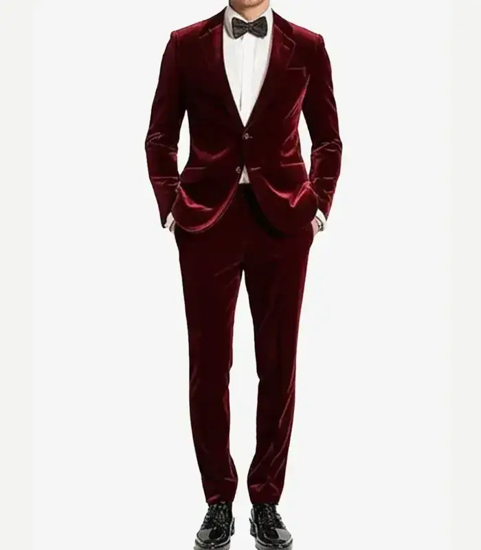 Front view of a man modeling a two-button maroon velvet tuxedo suit with a black bow tie, white dress shirt, and black patent shoes.