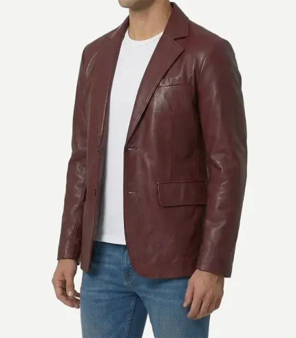 Three-quarter studio shot of a man modeling a stylish maroon leather blazer coat layered over a plain white t-shirt and blue jeans.